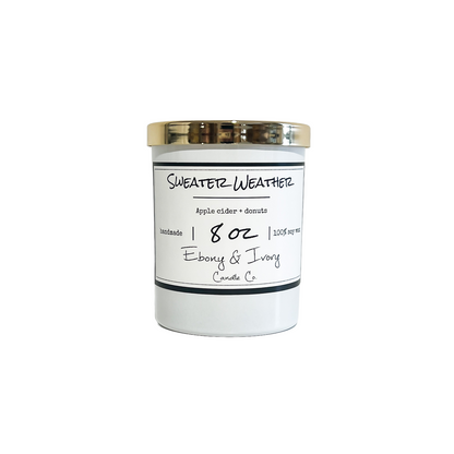 A white jar 8oz soy candle with a gold lid and a white label named Sweater Weather, on a white background, made by Ebony & Ivory Candle Co in Lethbridge, Alberta, Canada