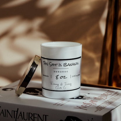 White soy candle with labels on a Yves Saint Laurent box against a blurred background.  Banana scented soy candle Canada.