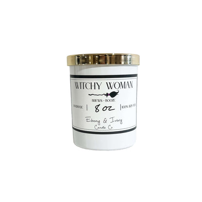 A white 8oz soy candle with a gold lid and a white label named "witchy woman"