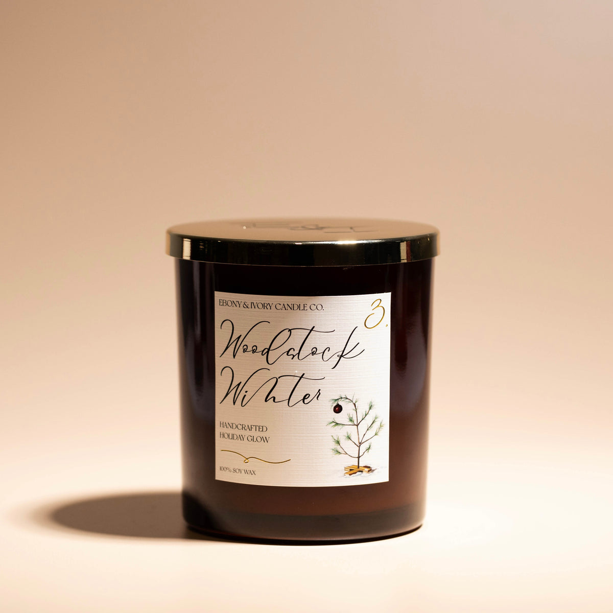 A 16oz amber soy christmas candle with a gold lid and a white label named "woodstock winter" on a beige background