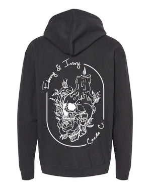 back of a Black, ebony and ivory candle co hoodie with a white design of a skull with a melting candle stick on it's head, surrounded by flowers