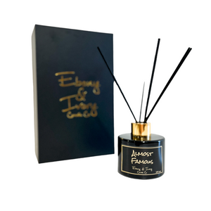 black one hundred milliliter, citrus, jasmine, and woodsy scented reed diffuser with a gold lid and a black label that reads Almost Famous