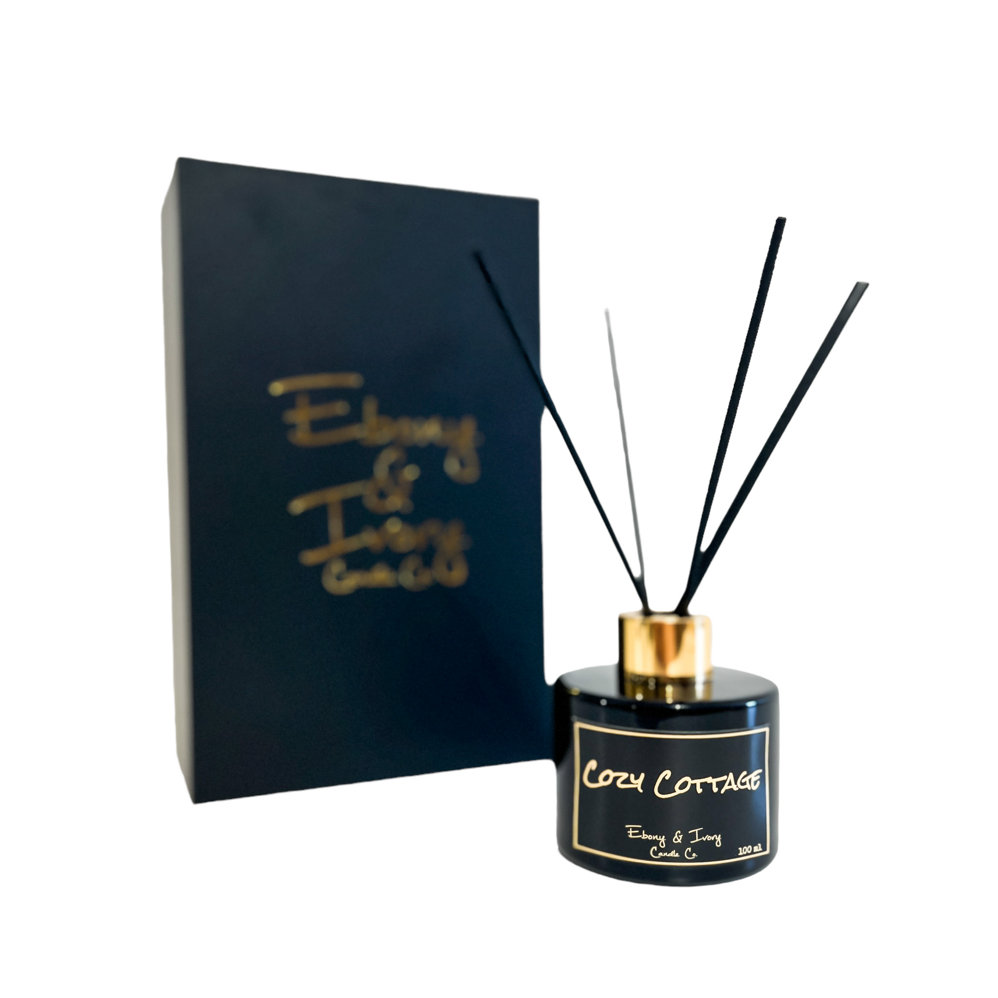 Black, one hundred milliliters, frozen pine, warm spice, and brown sugar scented reed diffuser with a gold lid and a black label that reads Cozy Cottage