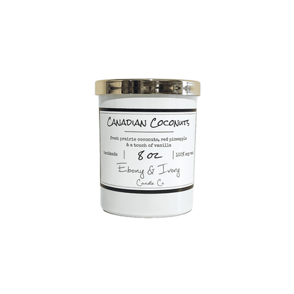 A white 8oz jar soy candle with a gold lid and a white label named Canadian Coconuts, on a white background, made by Ebony & Ivory Candle Co in Lethbridge, Alberta, Canada