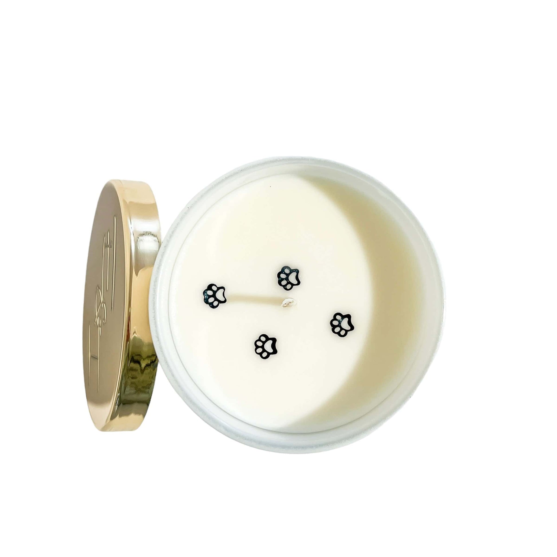 A top down view of a white 8oz soy candle with four black paw print glitters on top to look like a pet walking across. Made by Ebony & Ivory Candle co in Lethbridge Alberta Canada