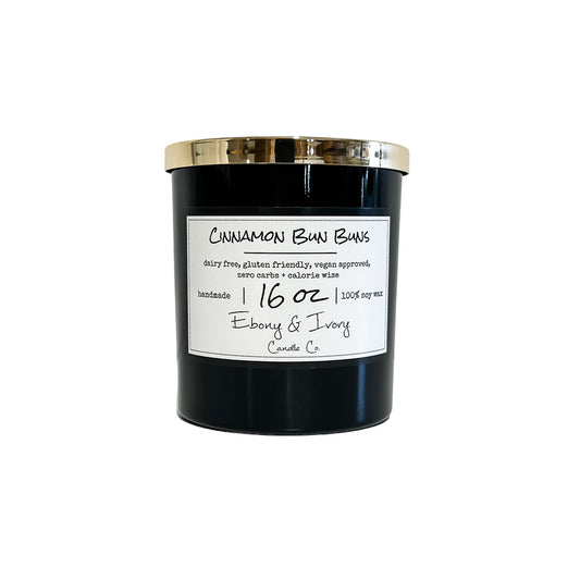 Black, sixteen ounces, cinnamon roll scented soy wax candle with a gold lid and a white label that reads Cinnamon Bun Buns