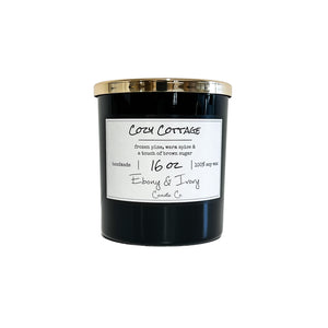 Black, sixteen ounces, frozen pine, warm spice, and brown sugar scented soy wax candle with a gold lid and a white label that reads Cozy Cottage