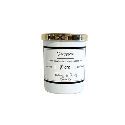 A white 8oz soy candle with a gold lid, labelled "Dog Mom" made by ebony & ivory candle co in lethbridge alberta canada