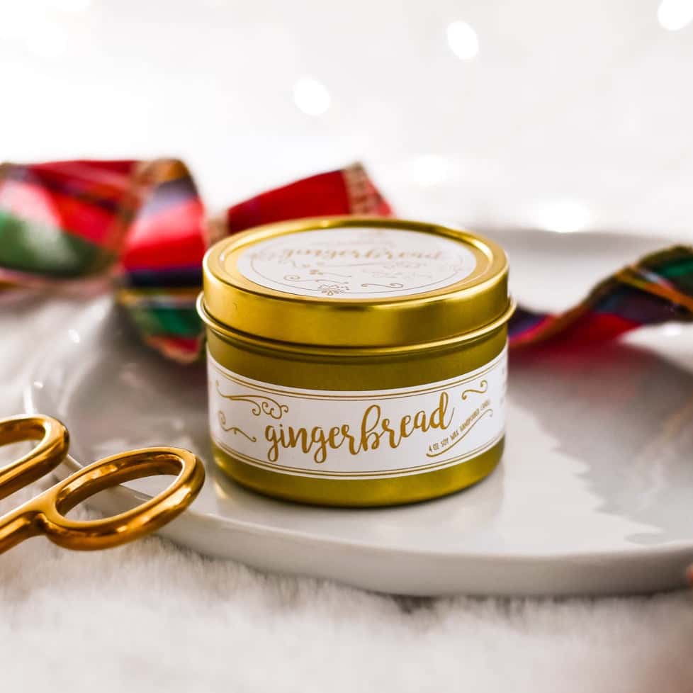 Gold, 4oz, gingerbread scented soy wax candle with a white label sitting on a tray with plaid christmas ribbon