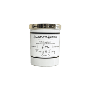 White, eight ounce, white tea, ginger, peach, and chardonnay scented soy wax candle with a gold lid and a white label that reads Hangover Heaven
