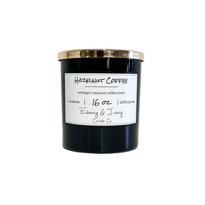 Black, sixteen ounce, coffee and hazelnut scented soy wax candle with a gold lid and a white label that reads Hazelnut Coffee