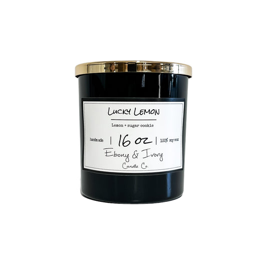 Black, sixteen ounce, lemon and sugar cookies scented soy wax candle with a gold lid and a white label