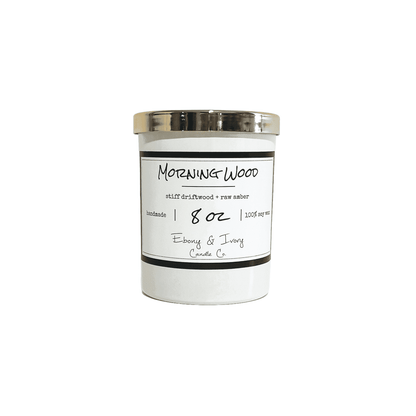 White, eight ounce, driftwood and amber scented soy wax candle with a gold lid and a white label that reads Morning Wood