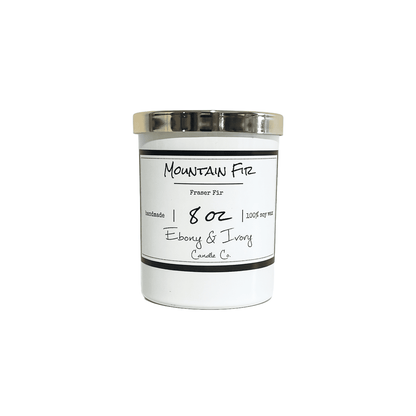 A white jar 8oz soy candle with a gold lid and a white label named Mountain Fir, on a white background, made by Ebony & Ivory Candle Co in Lethbridge, Alberta, Canada