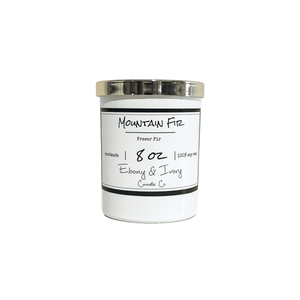 White, eight ounce, fraser fir tree scented soy wax candle with a gold lid and a white label that reads Mountain Fir