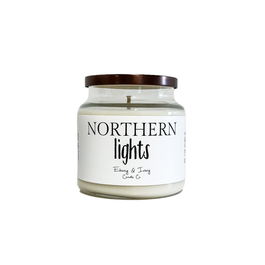 Clear glass, sixteen ounce, pine, cedar, eucalyptus, and lavender scented soy wax candle with a bronze lid and a white label that reads Northern Lights