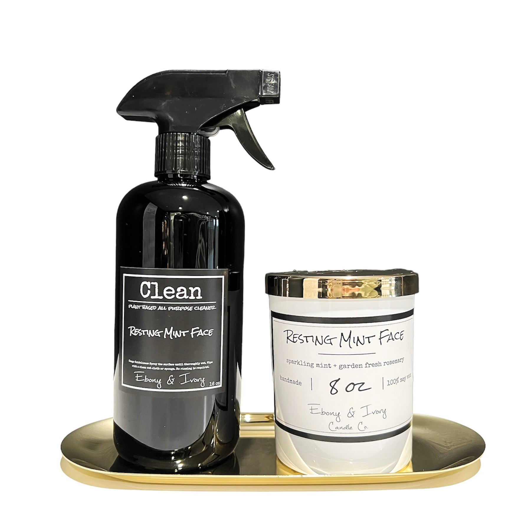Black spray bottle next to a white, eight ounce, mint and rosemary scented soy wax candle with a gold lid and a white label that reads Resting Mint Face