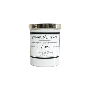 White, eight ounce, mint and rosemary scented soy wax candle with a gold lid and a white label that reads Resting Mint Face