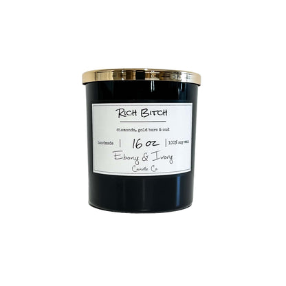 A black jar 16oz soy candle with a gold lid and a white label named Rich Bitch, on a white background, made by Ebony & Ivory Candle Co in Lethbridge, Alberta, Canada