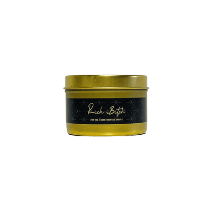 A gold 4oz tin soy candle with a black label named Rich Bitch, on a white background, made by Ebony & Ivory Candle Co in Lethbridge, Alberta, Canada