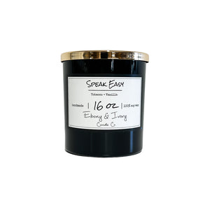 Black, sixteen ounce, tobacco and vanilla scented soy wax candle with a gold lid and a white label that reads Speak Easy