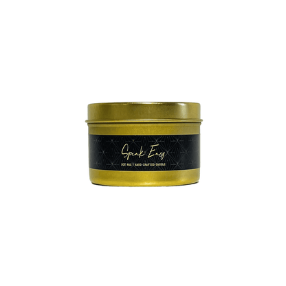 A gold 4oz tin soy candle with a black label named Speak Easy, on a white background, made by Ebony & Ivory Candle Co, in Lethbridge, Alberta, Canada