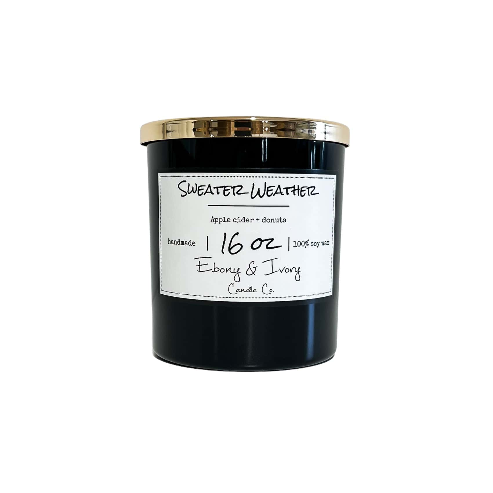 A black jar 16oz soy candle with a gold lid and a white label named Sweater Weather, on a white background, made by Ebony & Ivory Candle Co in Lethbridge, Alberta, Canada